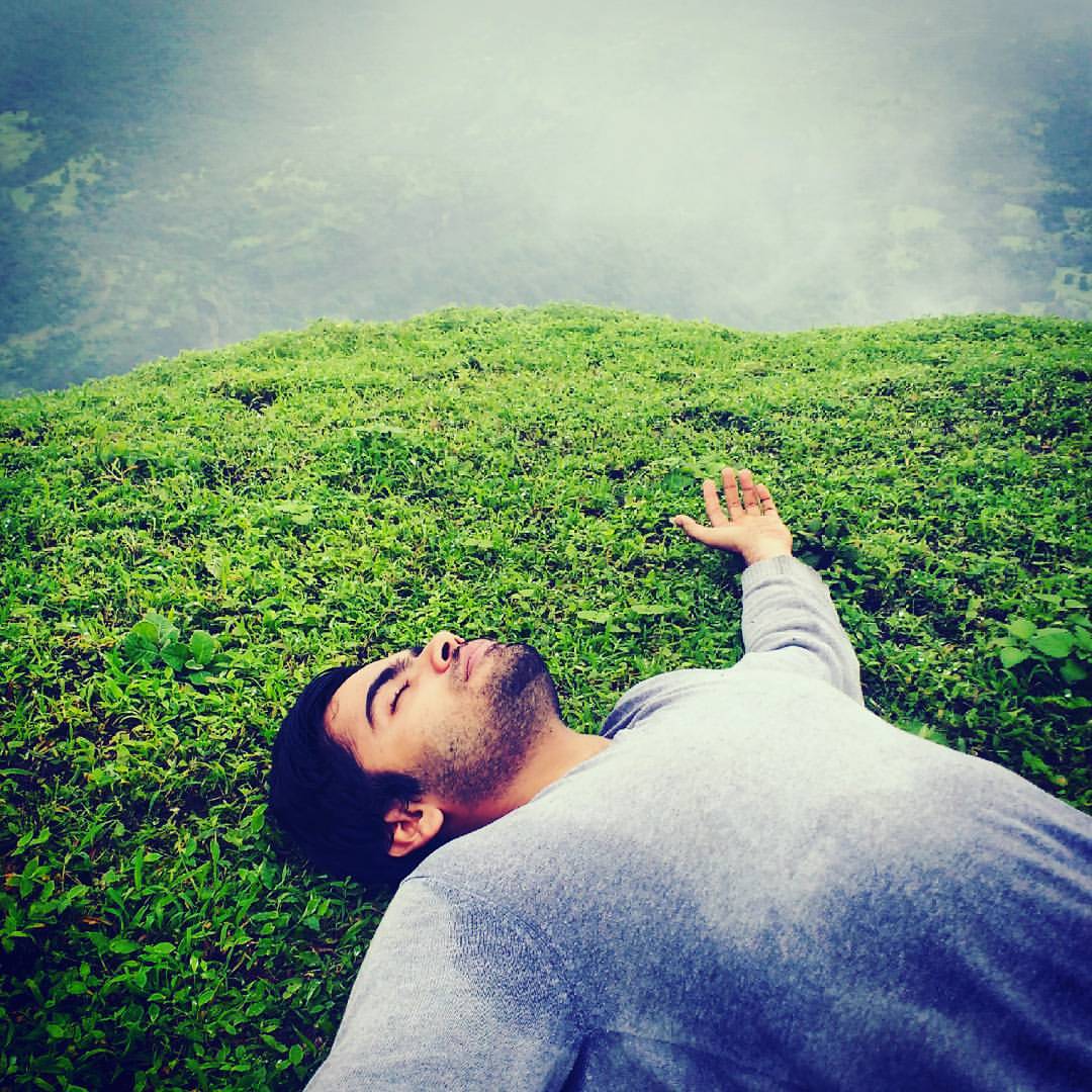 A man lying on his back in thick green grass, eyes closed